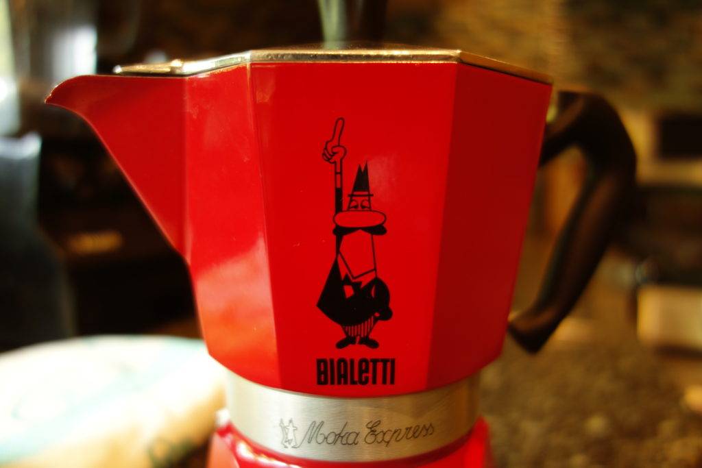 Moka pots are emblazoned with a caricature of Alfonso Bialetti “the little man with the mustache.” He has one finger up to order another espresso.